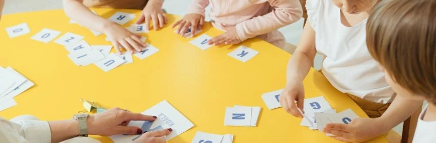 várias-criancas-na-mesa-brincando-com-letras-do-alfabeto